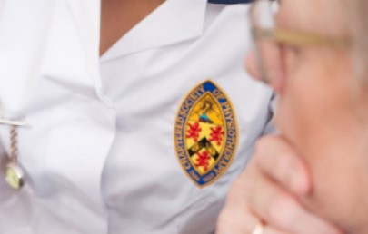 Physio in patient consultation with chartered badge on uniform