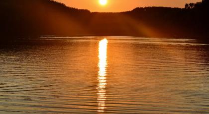 A calming image of the sun setting over a lake
