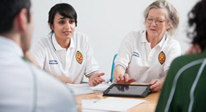 a group of physiotherapists in a meeting, one physio is showing the rest something on an ipad