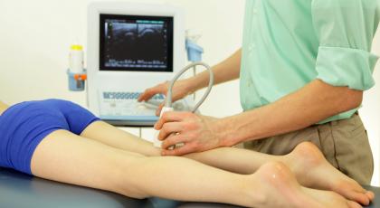 A technician performing an ultrasound on a patient's calf muscle
