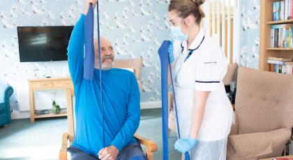 Physio shows elderly male patient arm stretch band