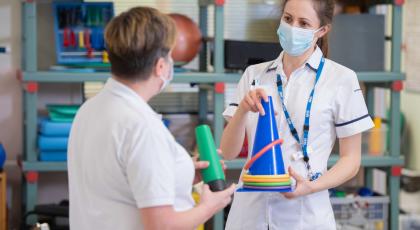 Two physios hold equipment in hospital rehab space