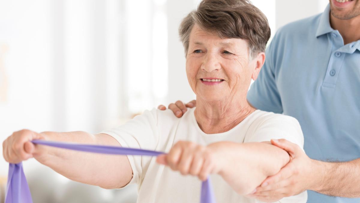 Rehab 1 Happy senior woman stretching with elastic tape during rehabilitation