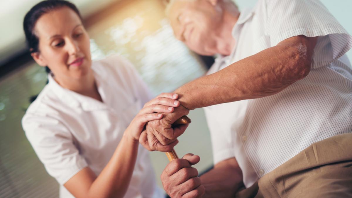 Physio holding hand of old man with walking stick