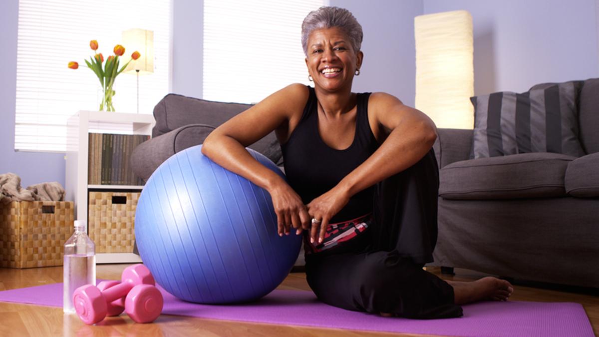 Woman on yoga mat A woman with a yoga mat, stability ball and handweights