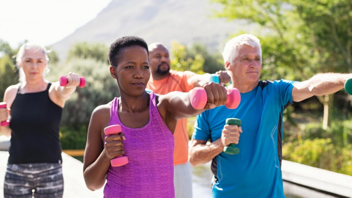 Healthy multiethnic people exercising using dumbbells outdoor to demonstrate strengthening exercises