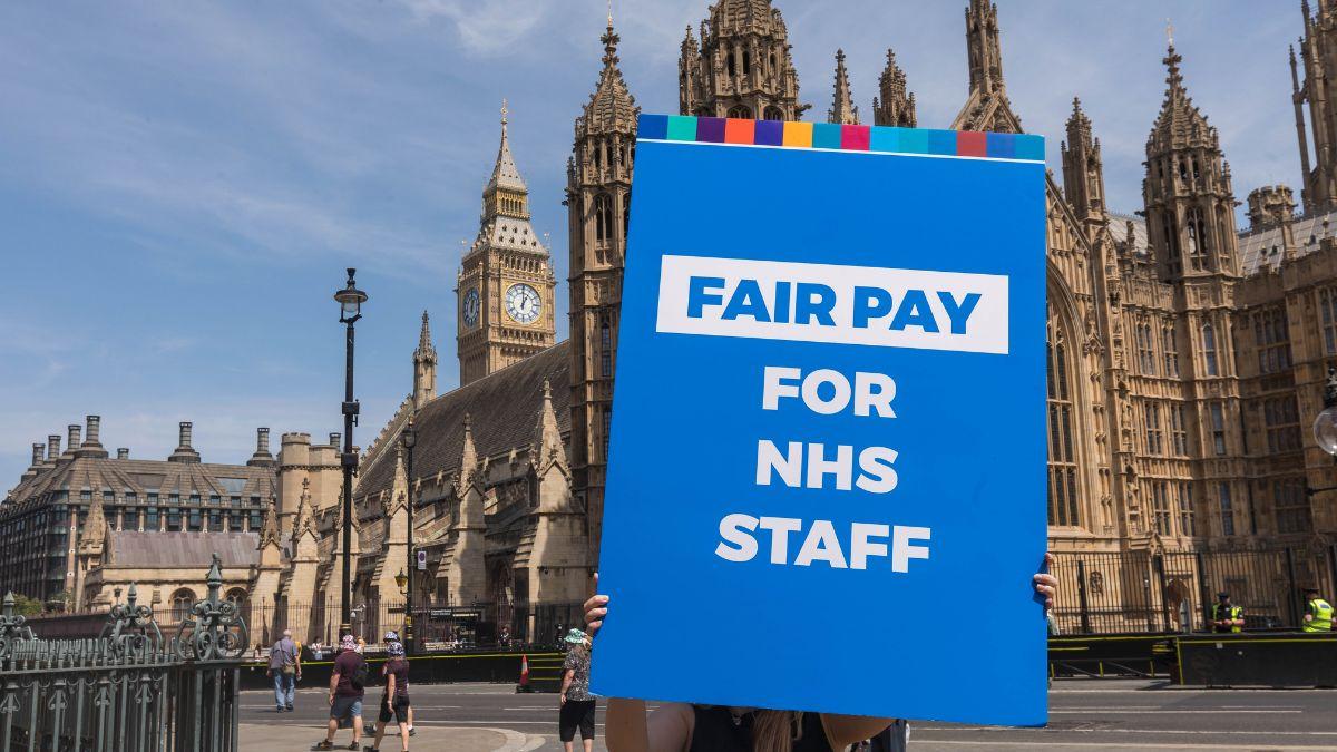 A Fair Pay for NHS staff sign is held up by a union representative in Westminster