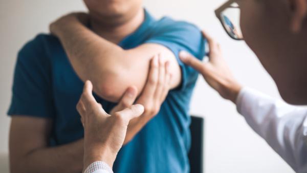 Man holding painful elbow Managing your elbow pain at home