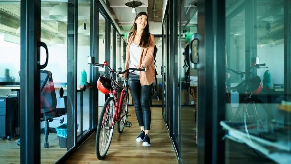 a woman wheeling a bike into her office