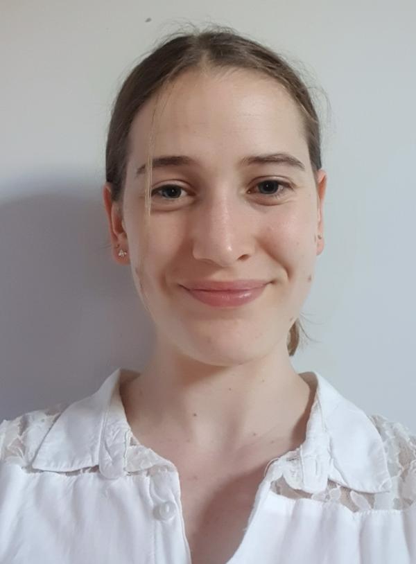 A woman in a white top with her hair tied back