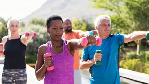 Healthy multiethnic people exercising using dumbbells outdoor to demonstrate strengthening exercises