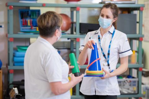 Two physios hold equipment in hospital rehab space