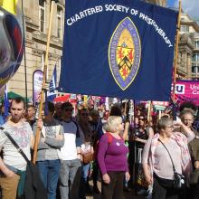 Members stand together beneath a CSP banner at a packed march