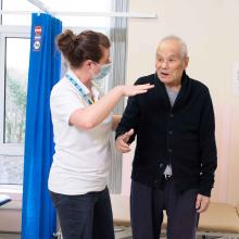 elderly man in hospital stands on pad as part of his rehab