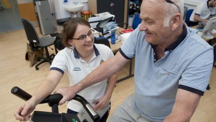 A prehab physio helps a patient exercise