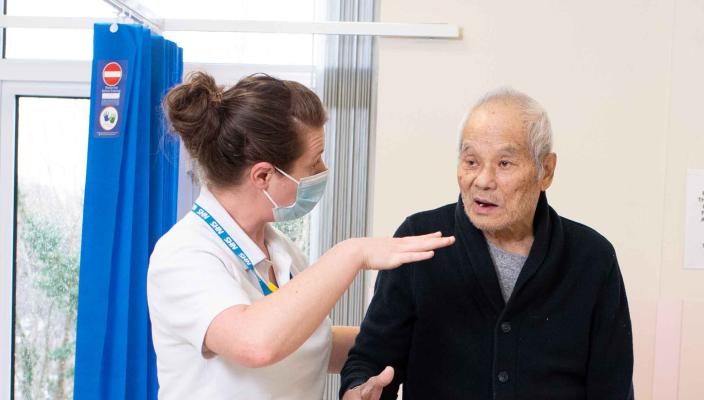 elderly man in hospital stands on pad as part of his rehab