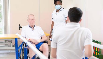 Two physios work with man in a wheelchair