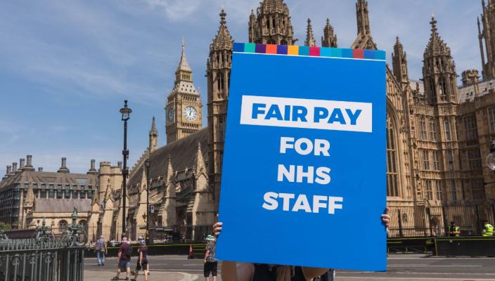 A Fair Pay for NHS staff sign is held up by a union representative in Westminster