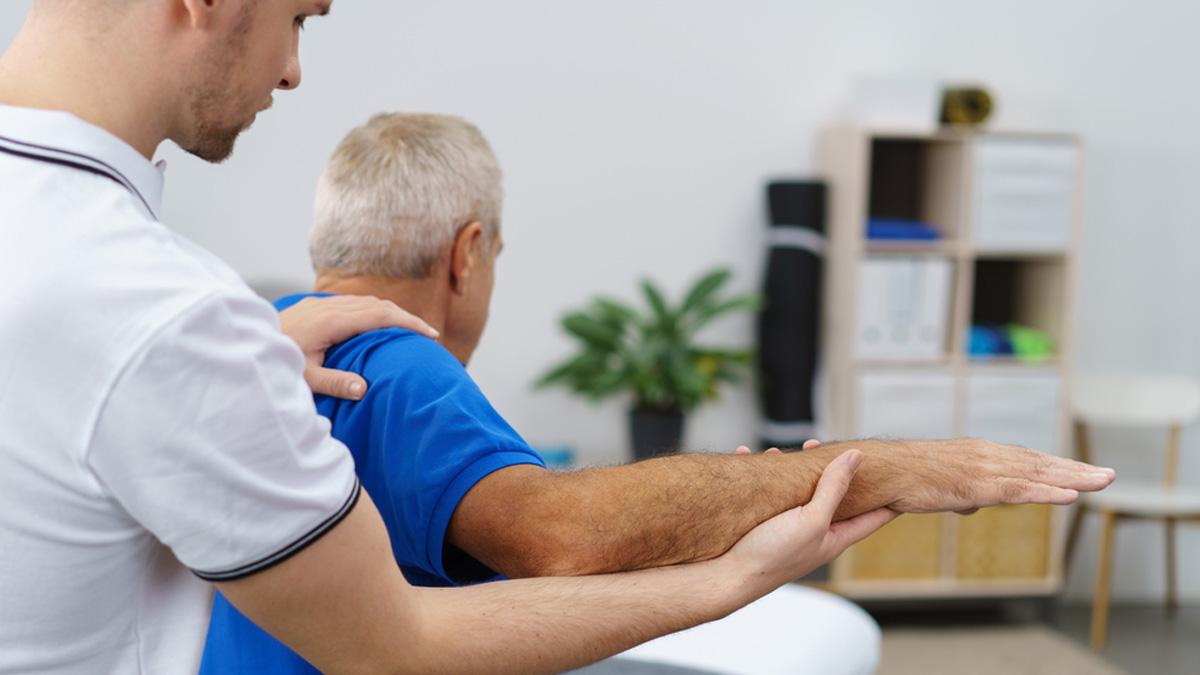 Physio giving treatment to man with elbow pain