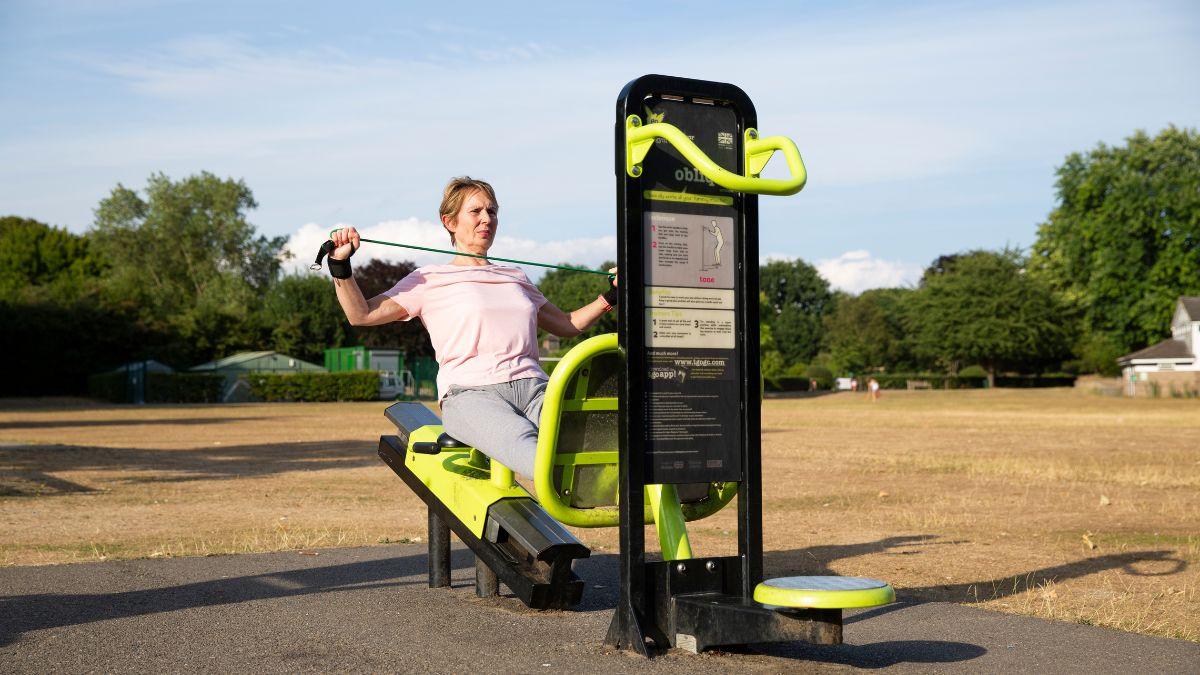 Photograph of a woman using a leg press and a resistance band at the park