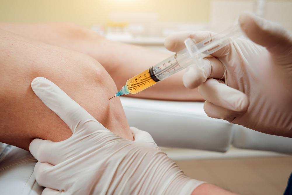 A healthcare professional administering a PRP injection to a patient's knee
