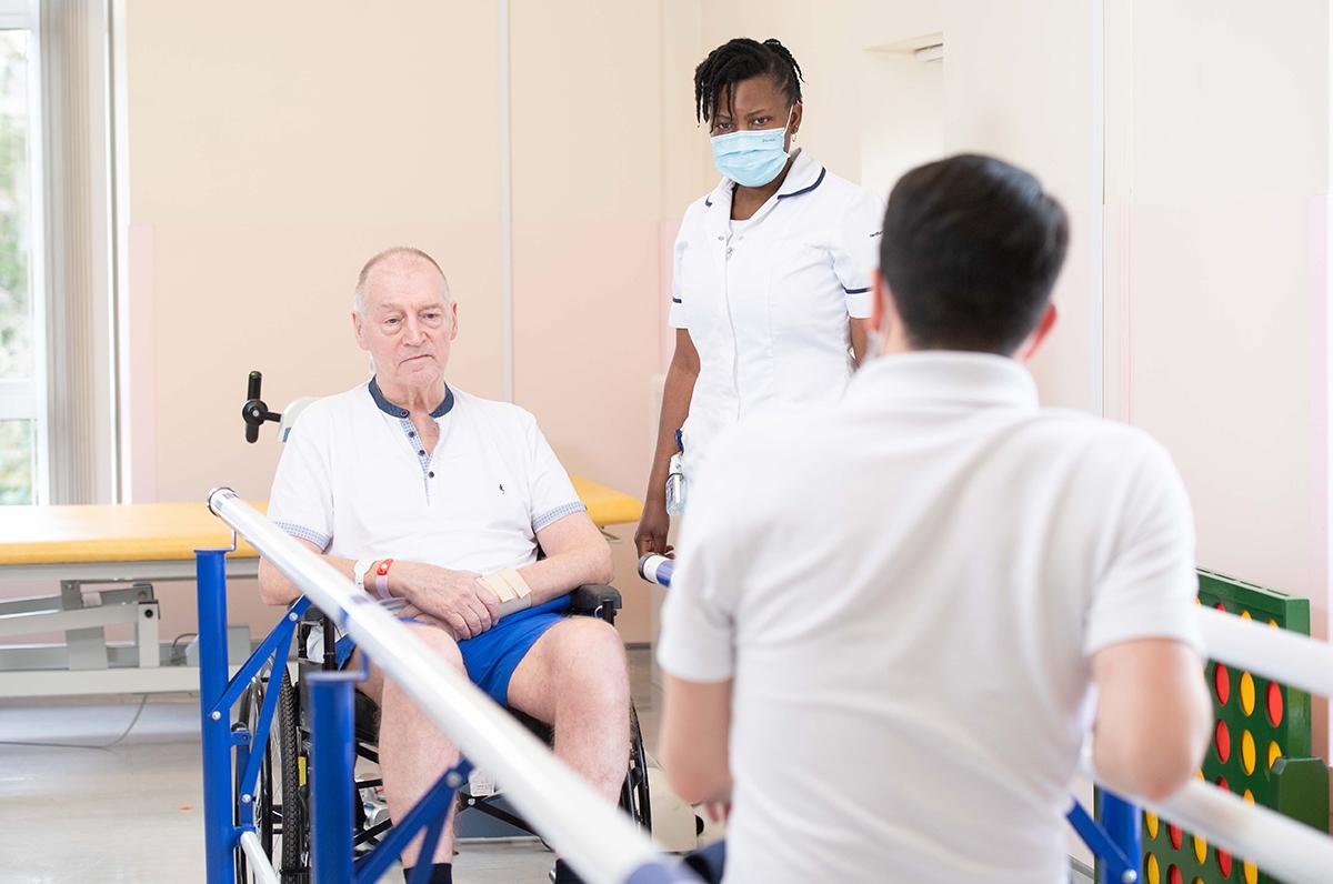 Two physios work with a man in a wheelchair