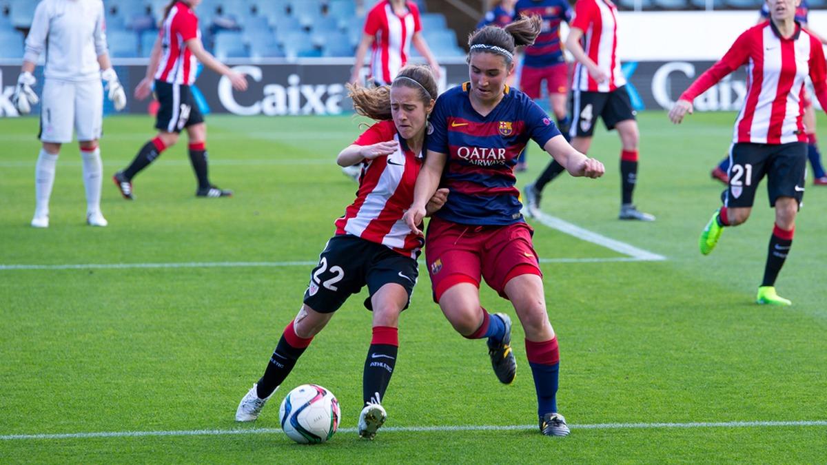two women playing a football match, one of them tackling the other to try to get the ball