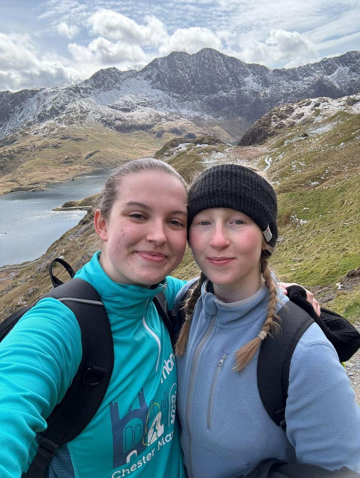 Hollie and Martha smiling at the camera. They are outdoors and there is mountains in the background.