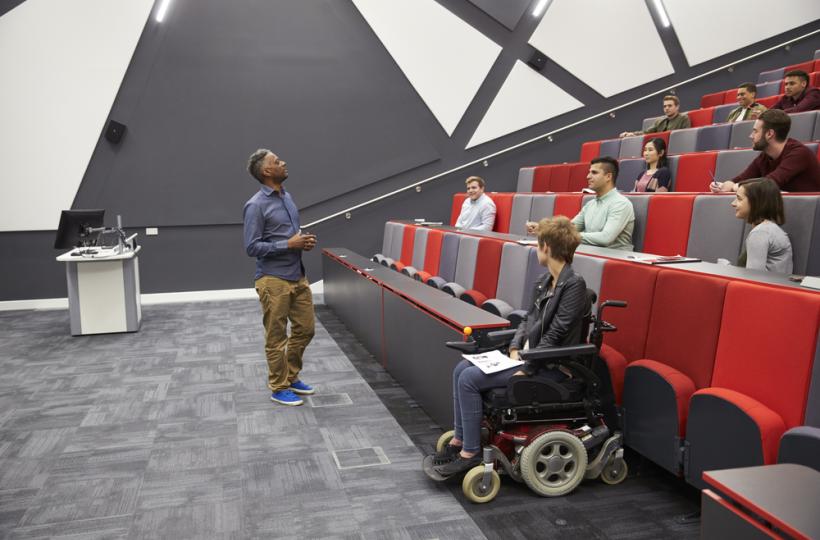 Man lecturing students in a university lecture theatre - one student is in a wheelchair
